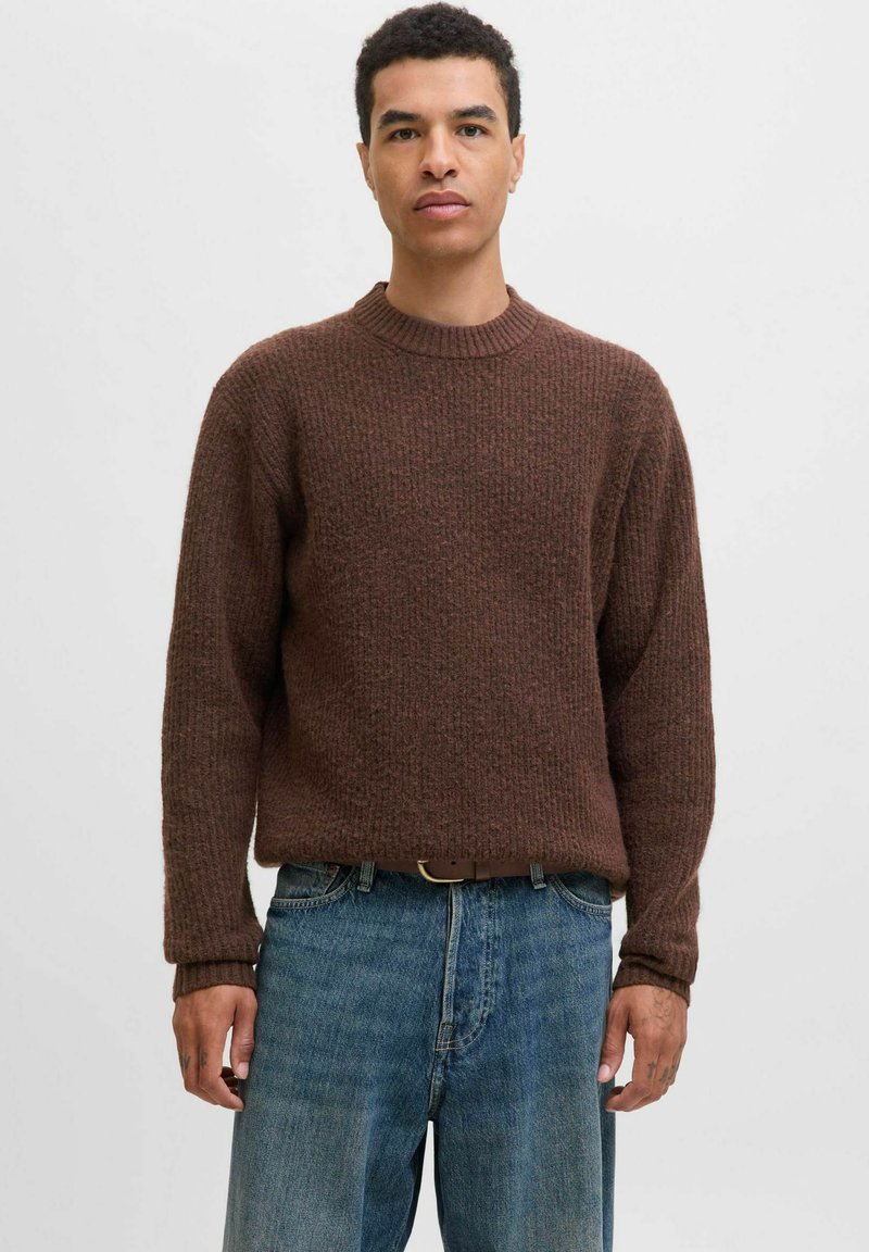 Bruin geribbeld gebreid sweater met een ronde hals, lange mouwen en een relaxte pasvorm, gecombineerd met blauwe denim jeans en een brown riem.
