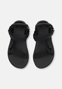 Mustat säädettävät hihnalliset sandaalit, valmistettu synteettisestä materiaalista. Niissä on teksturoitu pohjallinen ja joustava kumipohja.