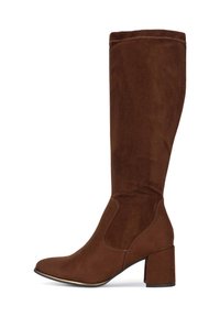 Bota marrón de ante hasta la rodilla con tacón ancho y punta redonda, detalle de costuras laterales y borde de suela negra con ribete dorado.