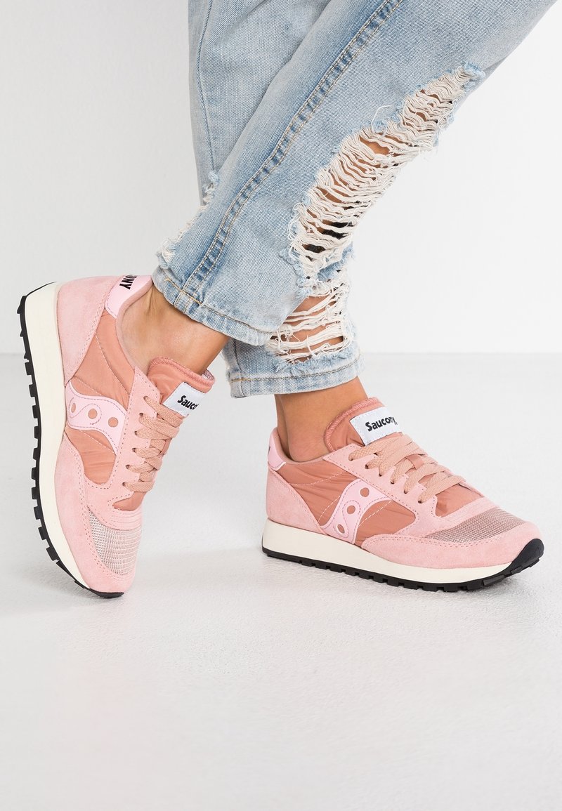 Des baskets rose clair en suède et mesh, avec une forme arrondie, un devant à lacets et des semelles extérieures en caoutchouc noir avec des semelles intermédiaires blanches.