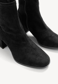 Crne antilop čizme do gležnja sa kvadratnim vrhom i blok petom. Imaju bočni patent zatvarač i glatku teksturu, što ističe moderan dizajn.