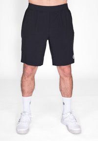 Schwarze Sportshorts in mittellanger Länge bis zum Oberschenkel, aus leichtem Material mit seitlichen Taschen und einem elastischen Bund. Kombiniert mit weißen Socken und Schuhen.
