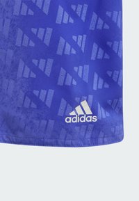 Maglia sportiva blu in tessuto traspirante, con un motivo geometrico e il logo Adidas bianco nell'angolo in basso a destra.