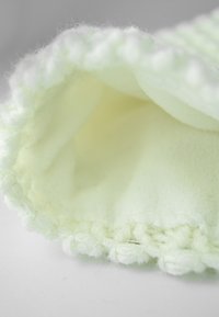 Light green fleece product with a soft, textured interior and a looped edge. The fabric appears cozy and inviting, ideal for warmth.