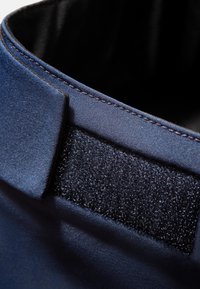 Niebieski materiałowy kołnierz w odcieniu granatu z matowym wykończeniem, charakteryzujący się gładką fakturą i paskiem z rzepem, starannie wykończone krawędzie widoczne.