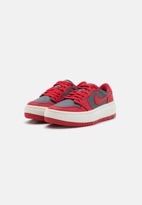 Baskets rouges et grises avec une tige en cuir lisse, un bout perforé et une semelle en caoutchouc blanche épaisse. Elles sont dotées de lacets rouges et d'un accent de logo.