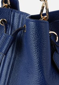Borsa a tracolla in pelle blu con finitura testurizzata. Presenta hardware dorato, una chiusura a coulisse e accenti metallici rotondi.