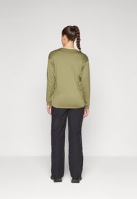 Long-sleeve olive green top with a round neckline, paired with black cargo pants. The top features a smooth texture and relaxed fit.
