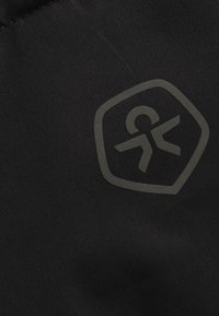 Tessuto nero con un logo testurizzato a forma di scudo, con una persona in movimento nel design. Superficie liscia, design minimalista.