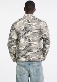 Camo-jack in beige en grijstinten, met een gekleurde kraag, knopenmanchetten en een ontspannen pasvorm. Opvallende textuur is katoen.