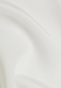Tissu blanc lisse avec des plis doux et des ombres subtiles créant des courbes et une texture délicates.