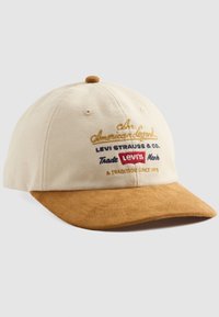 Beige and brown baseball cap with embroidered text "An American Legend Levi Strauss & Co. Trade Mark Levi's A Tradition Since 1873."