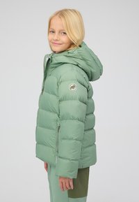 Gevoerde groene jas met een capuchon, voorzien van een rits en een geborduurd logo op de mouw. Zachte textuur en gestikte ontwerp.