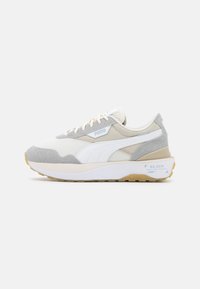Sneaker con tomaia in mesh bianco e suede grigio, dettagli beige e una suola spessa bianca. Presenta un piccolo logo blu. Suola esterna marrone chiaro.