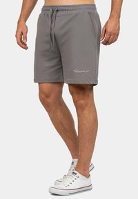 Shorts da nuoto grigi con vita elastica e cordino, dotati di tasche laterali e di un sottile logo bianco sulla gamba sinistra.