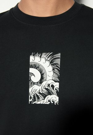 Černé tričko s krátkým rukávem má na hrudi bílý grafický motiv vln a slunce v obdélníkovém rámečku. Texturovaná látka.