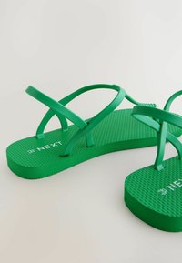 Rohelised kummist šlepid, millel on tekstureeritud jalanõud, ristuvad rihmad ja „NEXT“ logo trükituna tallale.
