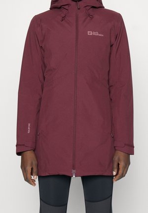 Bourgogne vandtæt jakke med hætte, fuld frontlynlås og logo på brystet, båret over sorte leggings.
