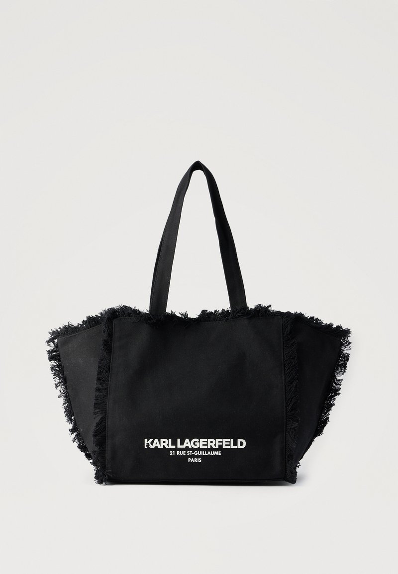 Μαύρη τσάντα tote από ύφασμα με κρόσσια στις άκρες και λευκό κείμενο "KARL LAGERFELD 21 RUE ST-GUILLAUME PARIS" στην μπροστινή τσέπη.