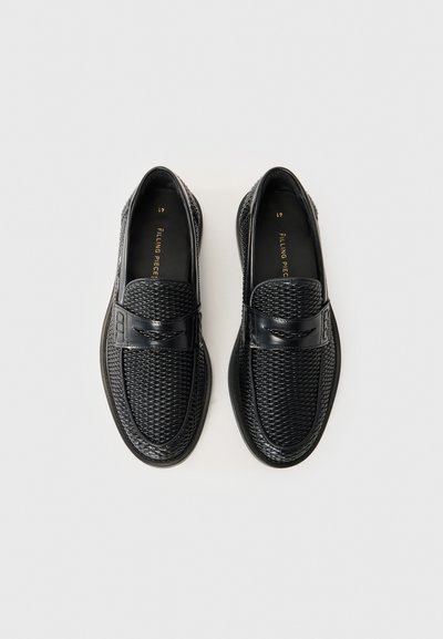 Ein Paar schwarze, geflochtene Lederloafer mit einem glatten Riemen oben, nebeneinander auf einem weißen Hintergrund präsentiert.