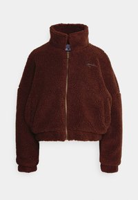 Brun fleecejakke med høy krage, full frontglidelås og litt kroppet design. Har overdimensjonerte ermer og brodert logo-detalj.