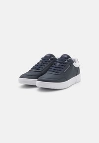 Mörkblå sneakers i läder med en vit gummisula, med snörningsdesign och logotyp på tungan och sidan.
