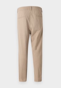 Pantalons beiges avec une taille plate et un dos élastique, dotés de deux poches arrière et d'une coupe fuselée. Tissu léger avec une texture lisse.