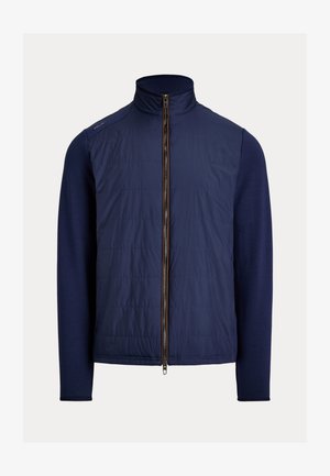 Giacca ibrida blu navy con davanti trapuntato, maniche lunghe a maglia, colletto rialzato e cerniera frontale completa.