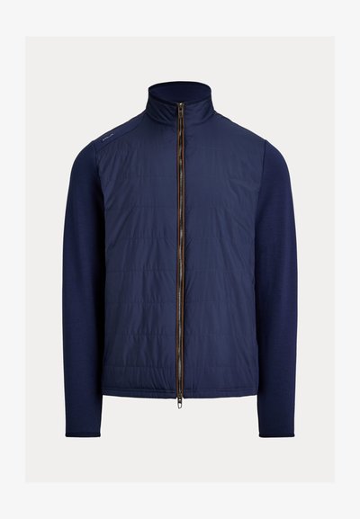 Chaqueta híbrida azul marino con parte delantera acolchada, mangas largas de punto, cuello perkins y cremallera frontal completa.