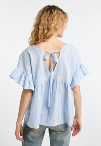 Lichtblauwe blouse met korte mouwen, ruches aan de mouwen, sluiting met strik aan de achterkant, verticale strepen en kanten details langs het lijfje.