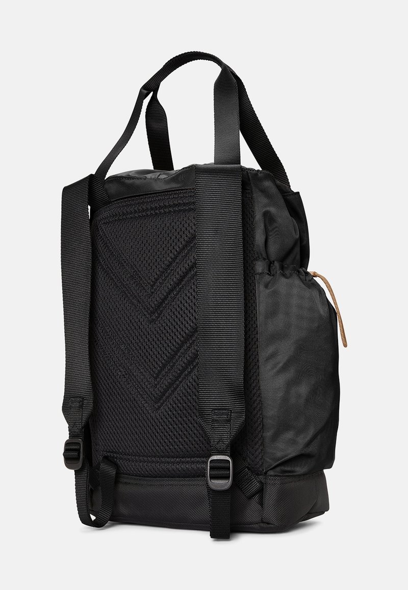 Zaino nero con un pannello in rete testurizzata, spallacci regolabili, tasca laterale con cordino e un notevole motivo di cucitura diagonale.