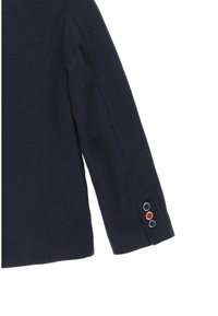 Giacca aderente blu navy con maniche in tessuto testurizzato, caratterizzata da dettagli con bottoni marroni e blu scuro sui polsini.