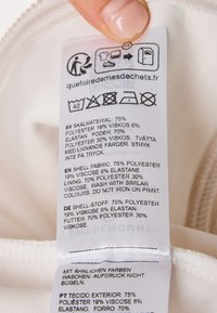 White fabric care label with washing instructions in multiple languages, detailing material composition: 75% polyester, 19% viscose, 6% elastane.