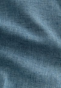 Textured fabric in shades of blue, featuring a woven pattern with small squares, soft surface, and a slight sheen.
