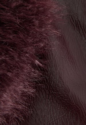 La fourrure bordeaux en peluche à gauche se transforme en une surface lisse et brillante marron avec une fine texture verticale à droite.