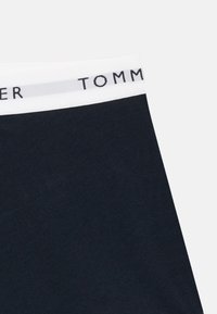Boxeri din bumbac bleu marin cu un tiv elastic alb, având inscripția "TOMMY" în text negru. Textură netedă, design clasic.