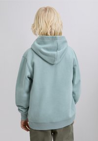 Jasnoniebieska bluza z kapturem wykonana z miękkiego materiału, z dużym kapturem, prążkowanymi mankietami i luźnym krojem. Gładka tekstura z minimalnymi detalami.