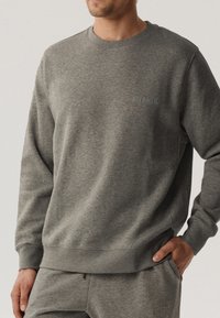 Szara bluza z okrągłym dekoltem i ściągaczami. Miękka tkanina bawełniana z domieszką zawiera subtelne logo "ATLANTIC" na piersi.