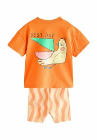Kortærmet orange t-shirt med teksten "BEDSTE DAG" og et tegneserie-fugle grafik, parret med beige shorts med bølgede orange striber.