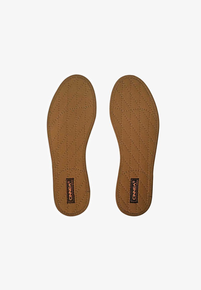 Brown quilted fabric insoles with a diamond pattern and a black label featuring the brand name "CINNEA." Soft texture, contour shape.