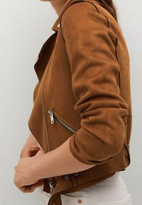 Giacca corta in suede marrone con zip frontale, maniche con risvolto e tasca laterale con zip. Tessuto liscio e dettagli di cucitura sottili.