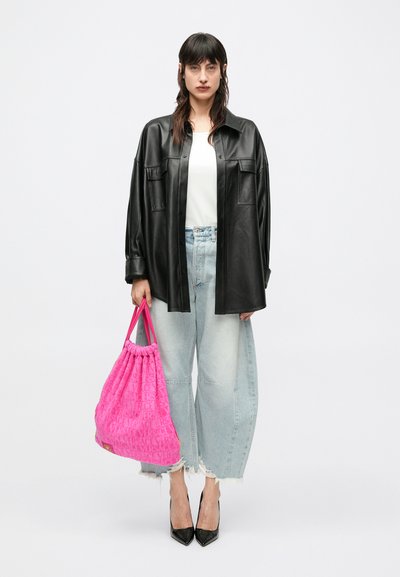 Crna kožna košulja širokog kroja, bijeli top, svijetloplave traperice visokog struka s poderanim rubovima i svijetloružičasta torba s logotipom i vezicom.