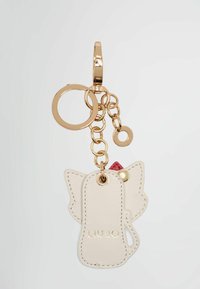 Portachiavi con una forma di gatto in pelle beige e hardware dorato, accentuato da un piccolo dettaglio rosso. "LIUJO" impresso in oro sul cartellino.