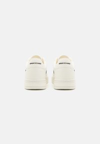 Weiße Sneakers aus Leder mit glatter Textur. Enthalten ein Logo auf der Ferse, eine geschichtete Sohle und ein minimalistisches Design.