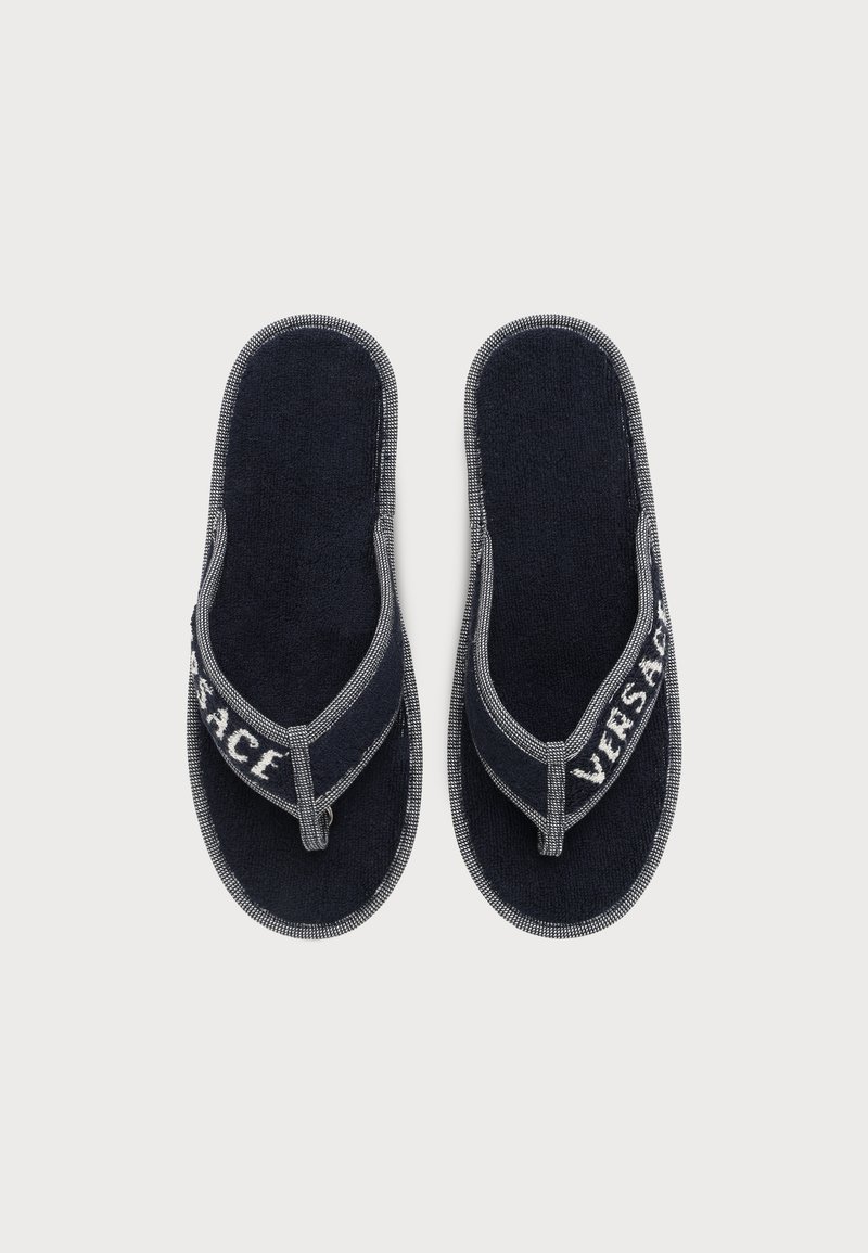 Pair of black fabric flip-flop slippers with gray trim, featuring the brand name "Versace" on the straps.