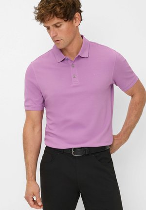 Polo shirt di colore viola chiaro con colletto e due bottoni, indossato con pantaloni neri. Branding discreto sul petto, maniche corte, texture liscia.