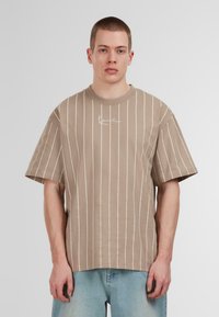 Brown short-sleeve T-shirt with white vertical stripes and a small logo on the chest. Made of soft fabric, features a relaxed fit.