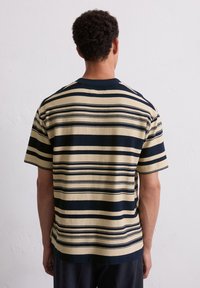 Striped knit short-sleeve shirt featuring horizontal navy and cream stripes, a crew neckline, and a textured fabric finish.