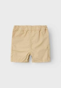 Pantalones cortos beige hechos de una tela ligera con una cinturilla elástica, dos bolsillos laterales y un corte relajado. Textura suave, longitud a mitad del muslo.