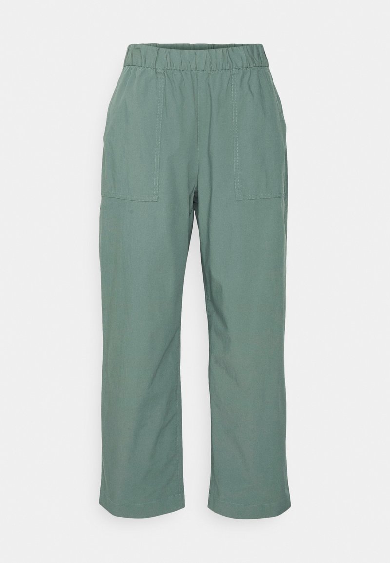 Pantalon taille élastique vert clair avec jambes droites et deux grandes poches plaquées à l’avant.